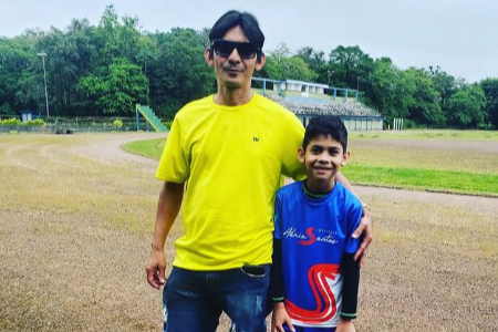 Imagem feita na pista de atletismo da Univille mostra pai e filho lado a lado. O pai abraça o filho