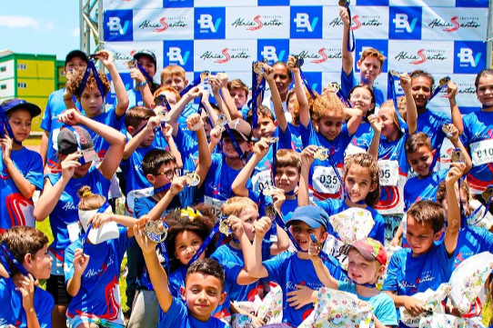 Imagem das crianças do Instituto com a atleta. A foto foi feita em frente o painel do Banco BV