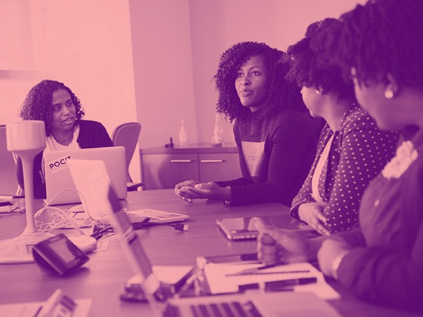 Cinnamon-toned photo of black women working at a desk with computers.