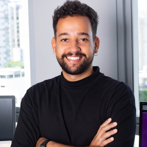 Photo of Denilson, who has brown skin, short dark hair, looking straight ahead and smiling.