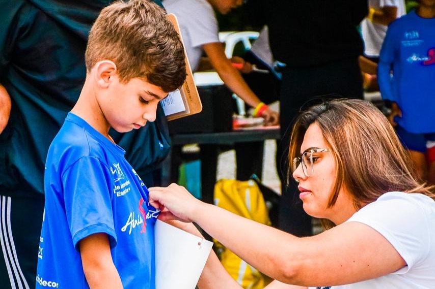 Mãe colocando o número de peito no aluno 