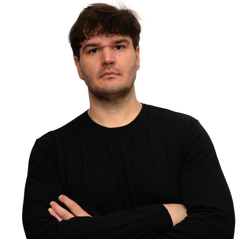 Homem branco, braços cruzados, cabelos curtos, roupa preta